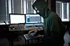 Male hacker in hood holds laptop, front view