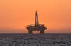 Sun setting behind oil drilling platform at Longbeach in Namibia