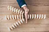 cropped view of risk manager protecting wooden blocks from domino effect
