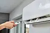 Hand adjusting temperature on air conditioner