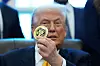 Donald Trump sitter i Det ovale kontor og viser frem et presidentielt challenge-coin.