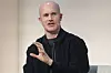 Brian Armstrong fra Coinbase gestikulerer mens han snakker på en konferansescene.