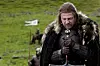 Eddard Stark står ute på en gressslette og holder et sverd mens han ser ned.