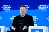 Elon Musk sitter på scene foran blå World Economic Forum-bakgrunn under panel.