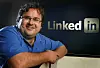 Reid Hoffman smiler foran en stor LinkedIn-logo på kontoret