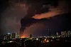 Nattbilde av Teheran med stor røyk- og ildsøyle fra brennende oljelager