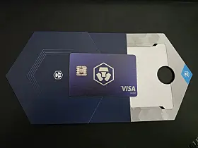 Crypto.com Visa-kort delvis ute av blå og hvit eske på svart bord