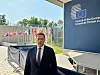Mann i dress foran Council of the European Union-bygning med EU-flaggrekke bak.