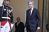 Bernard Arnault ankommer Élysée-palasset ved siden av en uniformert vakt i Paris.