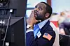 Aaron Ford sitter ved en skjerm på gulvet i New York-børsen og ser opp mens han holder en hånd mot ansiktet.
