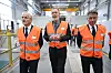Jonas Gahr Støre, Terje Aasland og Tom Huuse går gjennom et industrilokale i oransje vernevester.