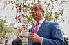 Nigel Farage holder en kopp te og møter støttespillere i London med britiske flagg i bakgrunnen.