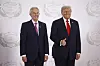 Donald Trump og Tony Blair står side om side og smiler foran en vegg med fredssummitlogoer.