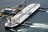 Råoljetankeren Idemitsu Maru seiler ved en kai utenfor Chita, med taubåter rundt skipet.