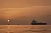 Soloppgang over et ankret tankskip i et rolig hav utenfor Qeshm Island, Iran.