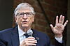 Bill Gates holder mikrofon og taler med hånden hevet under et arrangement i Berlin.