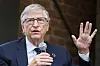 Bill Gates holder mikrofon og taler med hånden hevet under et arrangement i Berlin.