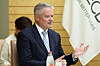 Mathias Cormann taler ved et møte i Tokyo med et OECD-flagg i bakgrunnen.
