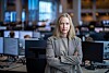 Kjersti Haugland står med armene i kors i DNBs meglerrom, omgitt av skjermer og arbeidsplasser.