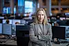 Kjersti Haugland står med armene i kors i DNBs meglerrom, omgitt av skjermer og arbeidsplasser.