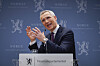 Jens Stoltenberg holder pressebriefing ved talerstol foran blå Finansdepartementet-bakgrunn.