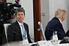 Sam Altman og Donald Trump sitter ved et møtebord under G7-toppmøtet, med kameraer og vannflasker i bakgrunnen.