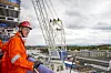 Person i oransje verneklær og hjelm på en kranplattform med utsikt over Rosenberg verft i Stavanger.