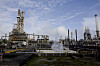 Equinors oljeraffineri på Mongstad med industrirør, anleggstårn og damp under blå himmel.