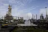 Equinors oljeraffineri på Mongstad med industrirør, anleggstårn og damp under blå himmel.