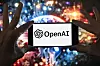 Mobil med OpenAI-logo foran et fargerikt, uskarpt bilde i bakgrunnen.