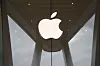 Stor Apple-logo over inngangen til en Apple-butikk med glassfasade.