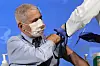 Dr. Anthony Fauci receives a COVID-19 vaccine injection from a masked healthcare worker.