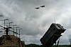 To F-16-jagerfly flyr over et Patriot-luftvernssystem i et ukjent område i Ukraina.
