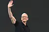 Tim Cook vinkar med armen hevet foran en mørk bakgrunn under Apples WWDC.