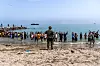 Spanske soldater blokkerer en strand i Ceuta mens en stor folkemengde står samlet ved vannet.