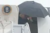 President Donald Trump går av Air Force One under en stor svart paraply ved Joint Base Andrews.