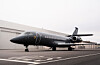 Mørk privatjet står parkert på en rullebane ved en flyplass.