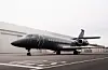 Mørk privatjet står parkert på en rullebane ved en flyplass.