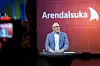 Nicolai Tangen står ved en talerstol på scenen foran en rød Arendalsuka-bakgrunn.