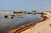 Oljerester ved en strand med fiskebåter og små brygger på Qeshm-øya i Iran.