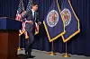 Kevin Warsh går bort fra en talerstol foran amerikanske flagg og bannere med Federal Reserves segl.