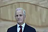 Statsminister Jonas Gahr Støre i dress og rødt slips foran en trepanelvegg.