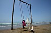 Kvinne skyver en jente på en huske ved stranden i Kuhestak i Iran.