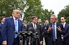 Donald Trump lytter til Jensen Huang foran Det hvite hus, omgitt av presse og andre politikere.