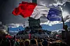 Et stort fransk flagg vaier over en folkemengde foran Triumfbuen i Paris.