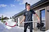 Johannes Høsflot Klæbo står med sportsutstyr utenfor en trehytte i snødekte omgivelser.