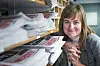 Mari Skurdal smiler bak stabler av Klassekampen-aviser i en redaksjon.