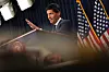 Kevin Warsh taler fra en talerstol foran amerikanske flagg under en pressekonferanse.
